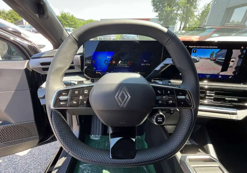 Vue centrée sur le volant noir perforé de la Renault Clio 6 TCE 115 EDC avec tableau de bord numérique et écran tactile.