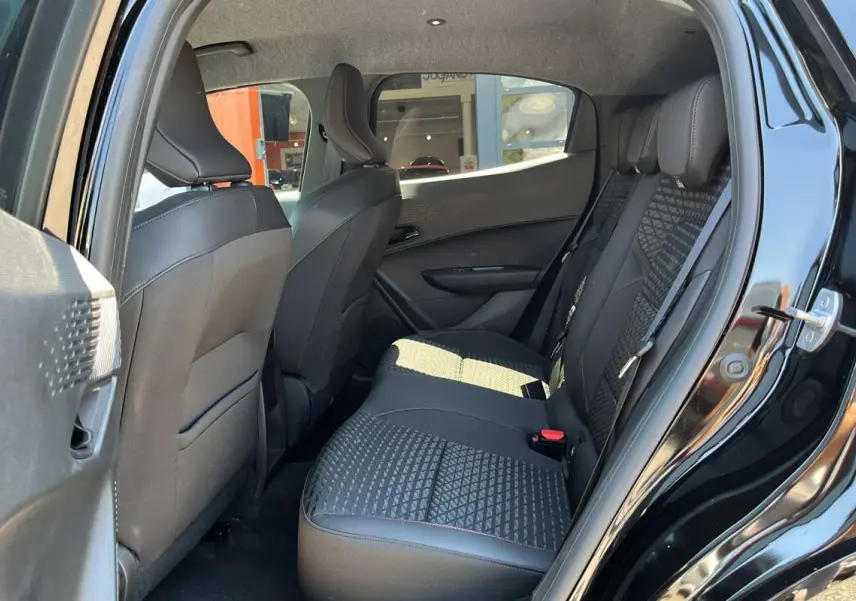 Vue côté gauche de l’intérieur arrière de la Renault Clio noir étoilé, sièges avec motif géométrique et surpiqûres rouges.