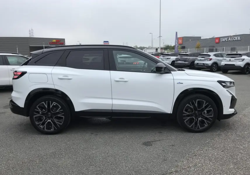 Profil droit du Renault Austral blanc bi-ton avec jantes alliage noires et toit noir satiné, en extérieur sur parking.