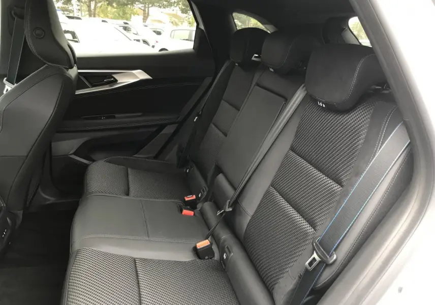 Vue intérieure côté droit des sièges arrière noirs en tissu carbone alcantara avec surpiqûres bleu blanc rouge du Renault Austral 2025.