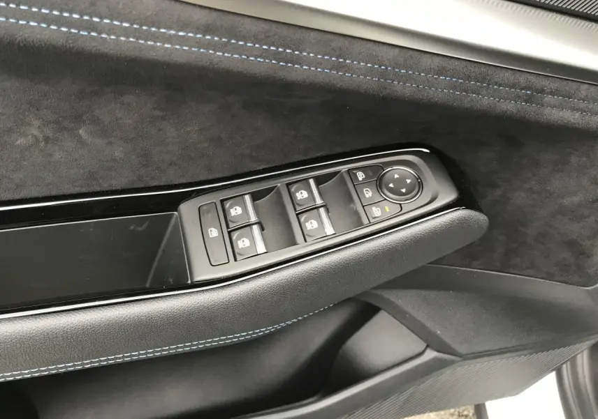 Détail de la porte côté conducteur du Renault Austral blanc, montrant les commandes des vitres et rétroviseurs avec surpiqûres bleues.