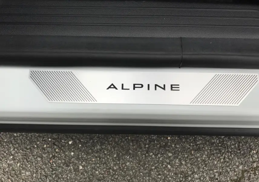 Gros plan sur le seuil de porte blanc du Renault Austral Esprit Alpine avec logo ALPINE et bandes grises.