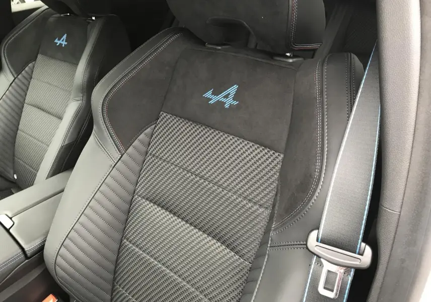 Gros plan sur les sièges avant noirs du Renault Austral Esprit Alpine avec logo bleu et surpiqûres colorées.