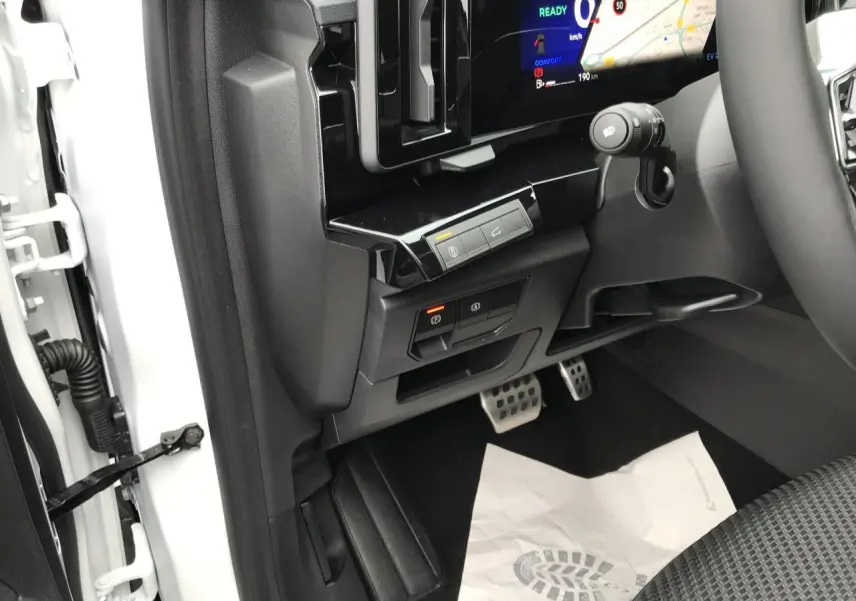 Vue intérieure côté conducteur du Renault Austral blanc, montrant les pédales, commandes électroniques et partie du tableau de bord numérique.