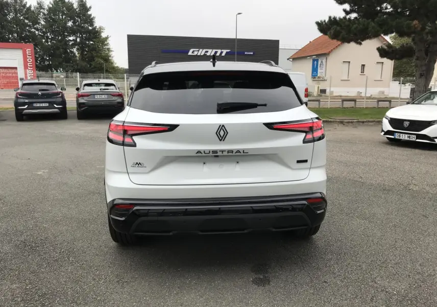 Vue arrière d'un Renault Austral blanc avec feux LED effilés et logo central sur un parking extérieur.