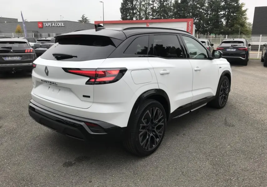 Vue 3/4 arrière droite du Renault Austral blanc bi-ton avec jantes noires et toit noir satin, en extérieur sur parking.