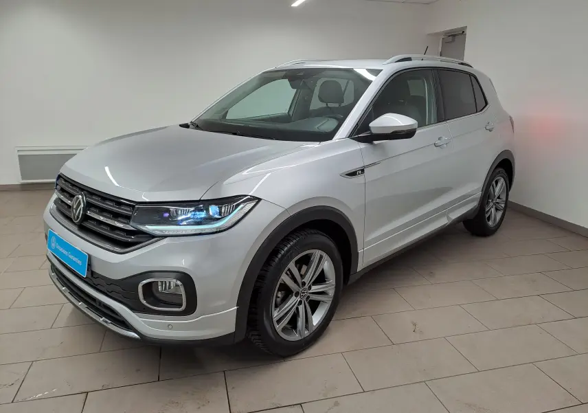 Volkswagen T-Cross 2022 argent reflet, vue 3/4 avant droit, avec badge R-Line et phares LED allumés.