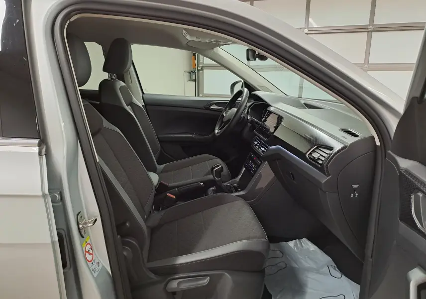Intérieur avant droit du Volkswagen T-Cross 2022 reflet d'argent, sièges tissu noir avec surpiqûres et tableau de bord moderne.