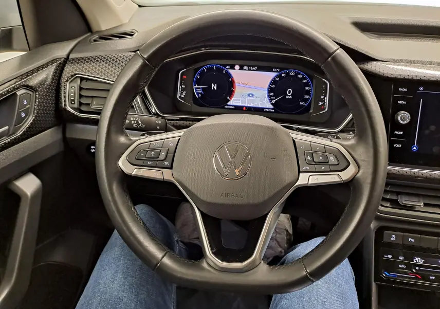 Vue intérieure centrée sur le volant noir du Volkswagen T-Cross 2022 R-Line avec tableau de bord digital et détails argentés.