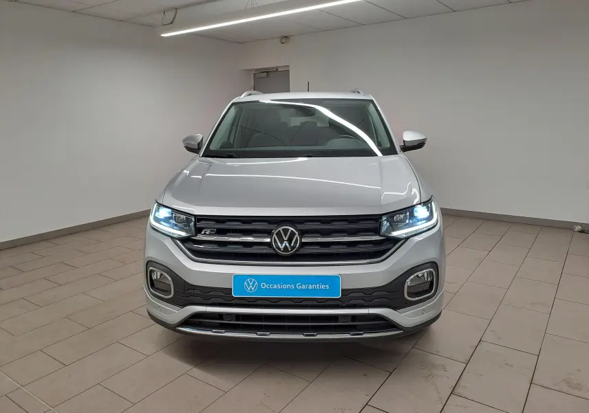 Volkswagen T-Cross 1.0 TSI R-Line 2022 en reflet d'argent, vue frontale avec phares allumés en intérieur.