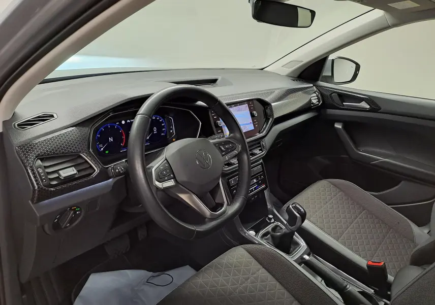 Vue intérieure côté conducteur du Volkswagen T-Cross 2022, tableau de bord moderne avec écran tactile et volant multifonction noir.