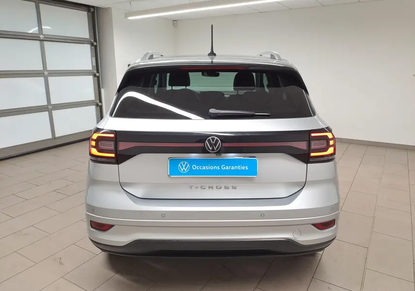 Vue arrière d'un Volkswagen T-Cross 2022 argent reflet avec feux LED allumés et logo VW centré sur le hayon.