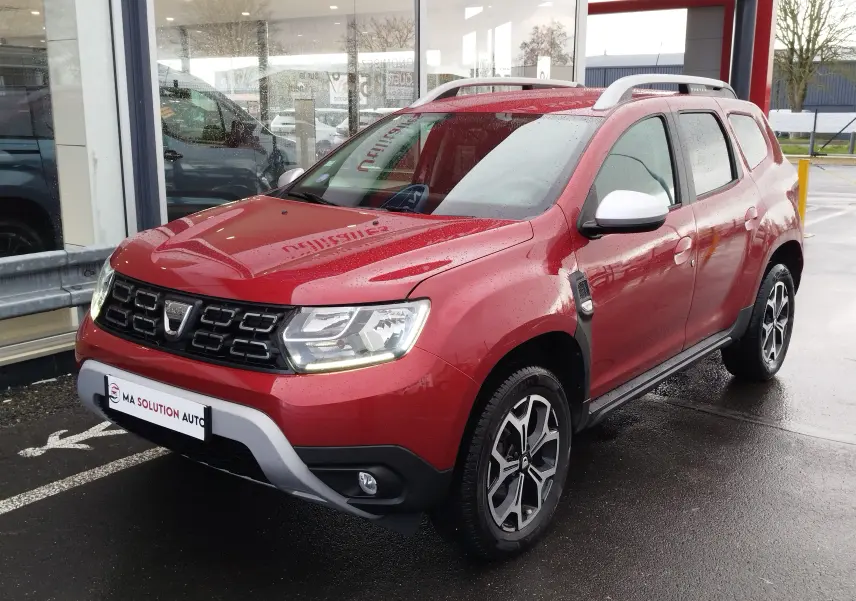 Vue 3/4 avant droite du Dacia Duster rouge fusion 2020 avec jantes bi-ton et rétroviseurs blancs.