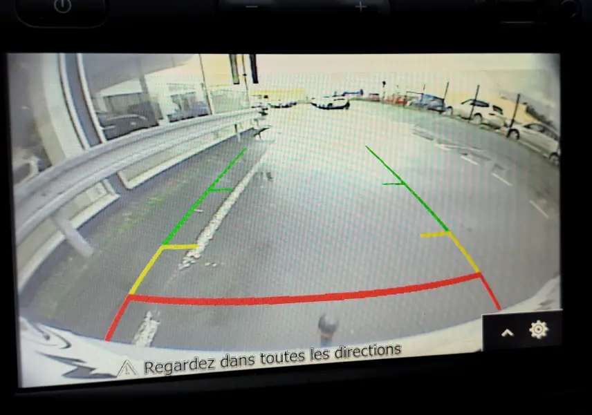 Vue caméra de recul du Dacia Duster rouge Fusion 2020, montrant les lignes de guidage colorées sur un parking extérieur.