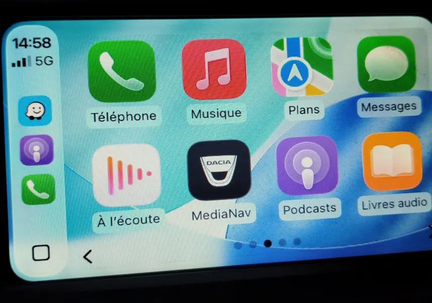 Écran tactile du système MediaNav de Dacia affichant plusieurs applications, avec l'icône Dacia au centre.