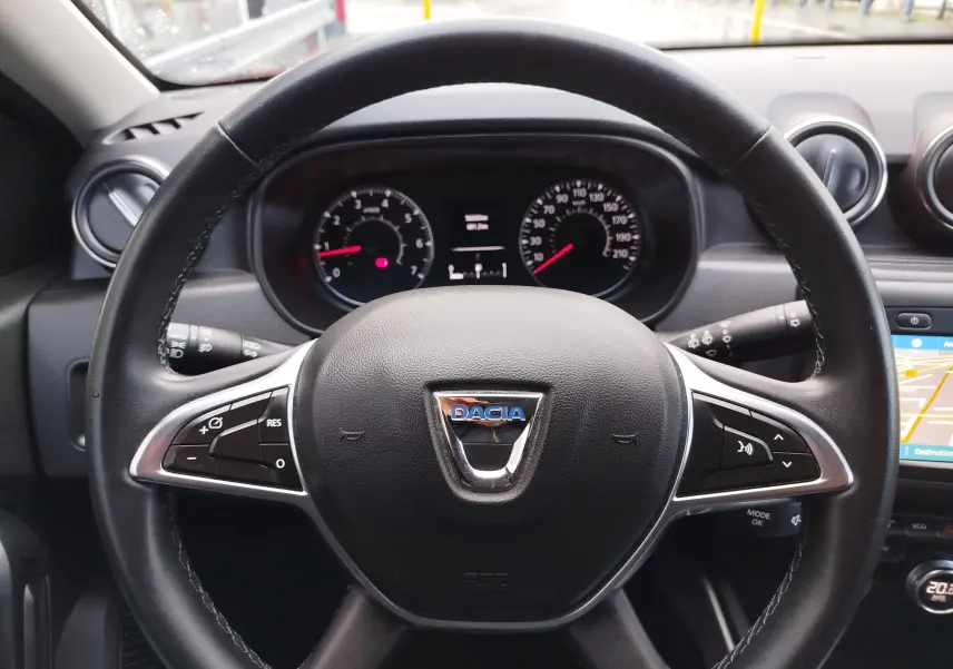 Vue rapprochée du volant noir de la Dacia Duster 2020 avec logo central et commandes intégrées.