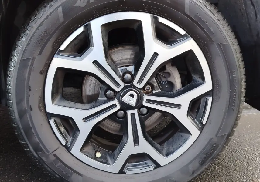 Gros plan sur la jante alliage bi-ton et pneu Hankook du Dacia Duster Rouge Fusion, mettant en valeur le logo central DACIA.