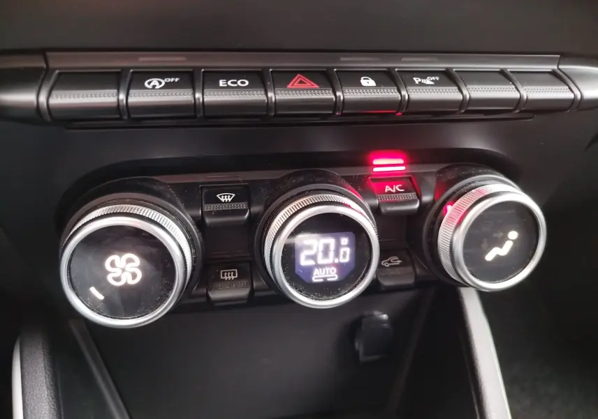 Gros plan sur la console centrale du Dacia Duster 2020, montrant les commandes de climatisation et les boutons de fonction rétroéclairés.