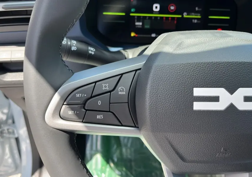 Gros plan sur le volant cuir du Dacia Bigster 2025 avec commandes multifonctions et tableau de bord numérique en arrière-plan.