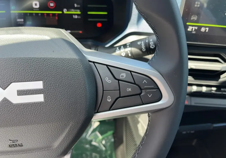 Gros plan sur le volant cuir du Dacia Bigster 2025, montrant les commandes multifonctions côté droit et l'écran digital en arrière-plan.