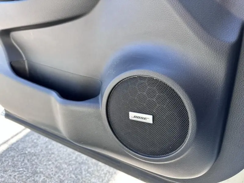 Gros plan sur l'enceinte Bose intégrée dans la porte intérieure noire du Nissan Qashqai blanc 2019 côté gauche.