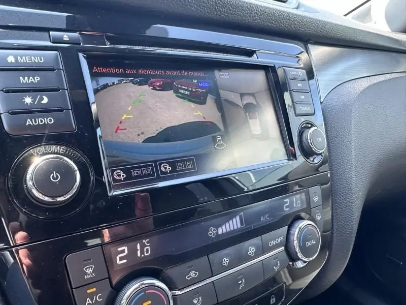 Vue rapprochée de l’écran multimédia du Nissan Qashqai 2019 blanc, affichant la caméra de recul et les commandes climatisation.