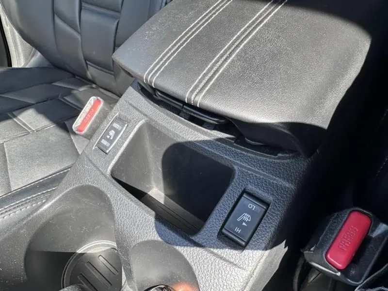 Détail de la console centrale noire avec accoudoir et boutons de réglage dans un Nissan Qashqai blanc 2019.