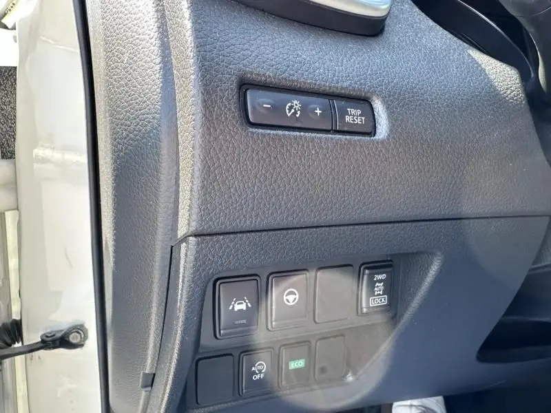 Gros plan sur les commandes de tableau de bord noir du Nissan Qashqai blanc 2019, avec boutons d’assistance et modes de conduite.