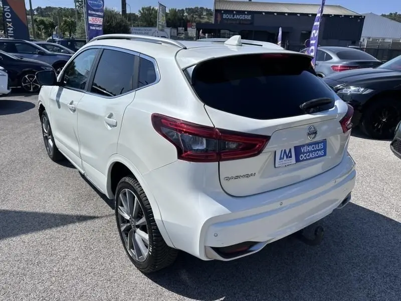 Vue 3/4 arrière droite d'un Nissan Qashqai blanc 2019 avec vitres teintées et jantes alliage foncé.
