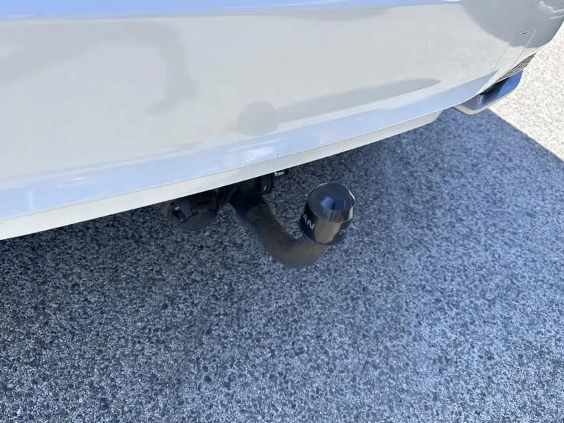 Gros plan sur l'attelage de remorque fixé à l'arrière d'un Nissan Qashqai blanc, vue centrée sur le pare-chocs inférieur.