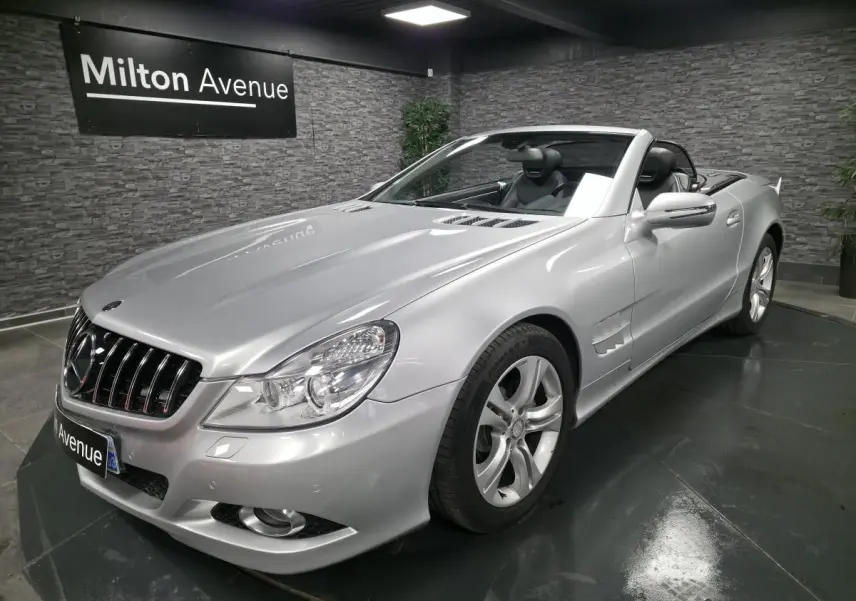 Mercedes SL 350 gris vue 3/4 avant droit, cabriolet avec jantes alliage et intérieur cuir noir visible.