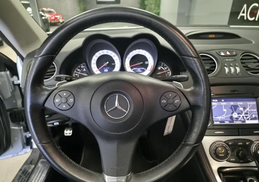 Vue intérieure centrée sur le volant cuir noir AMG d'une Mercedes SL 350 gris, avec tableau de bord et écran de navigation visibles.