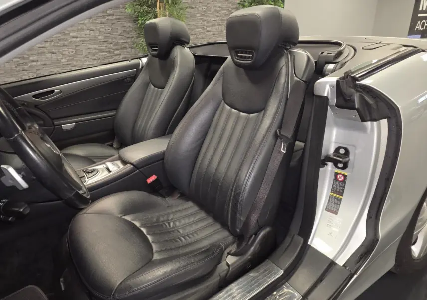 Vue intérieure côté conducteur de la Mercedes SL 350 gris, sièges cuir noirs et console centrale visible.