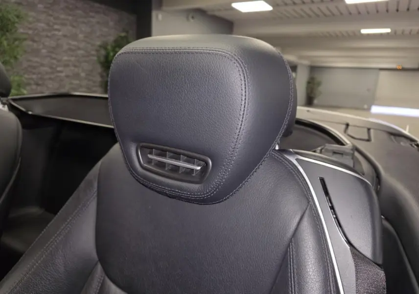 Gros plan sur l’appuie-tête en cuir noir du siège avant droit d’une Mercedes SL 350 gris, intérieur ouvert.
