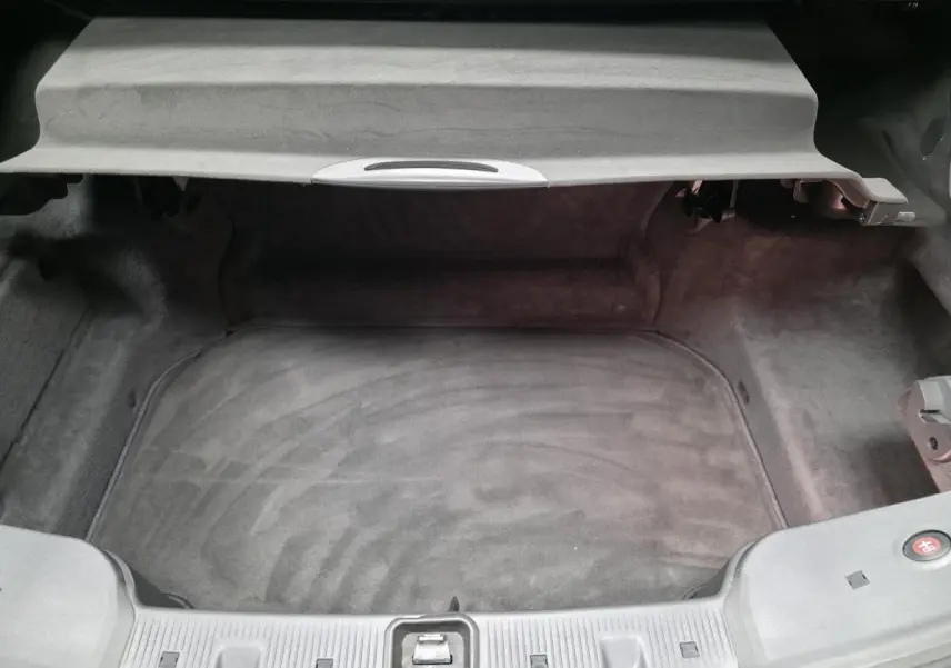 Vue plongeante sur le coffre spacieux et propre d'une Mercedes SL 350 gris, avec cache-moyeu bleu visible.