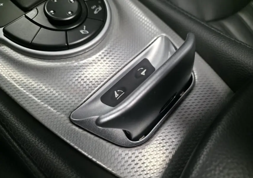 Détail du bouton de commande du toit rigide escamotable sur la console centrale en aluminium brossé d’une Mercedes SL 350 gris.