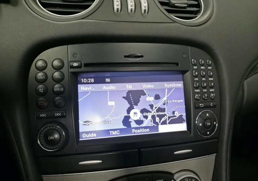 Vue rapprochée de l’écran de navigation COMAND APS et des commandes noires du tableau de bord intérieur d’une Mercedes SL gris 2009.