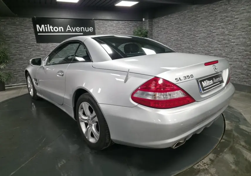 Vue 3/4 arrière droite d'une Mercedes SL 350 gris métallisé avec jantes alliage et toit rigide fermé.