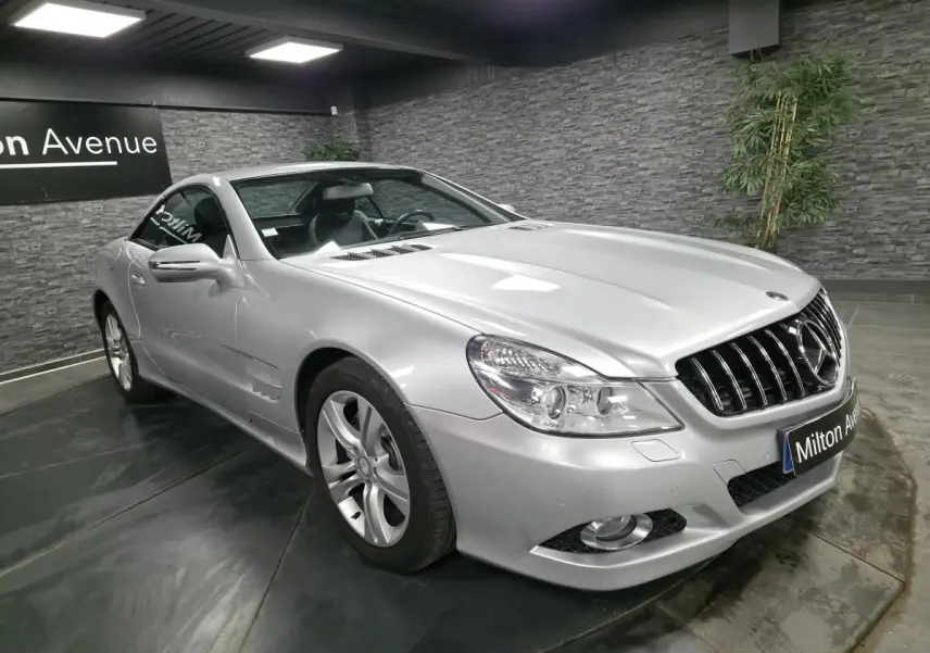 Vue 3/4 avant droite d'une Mercedes SL 350 gris métallisé avec jantes alliage et calandre chromée dans un showroom.