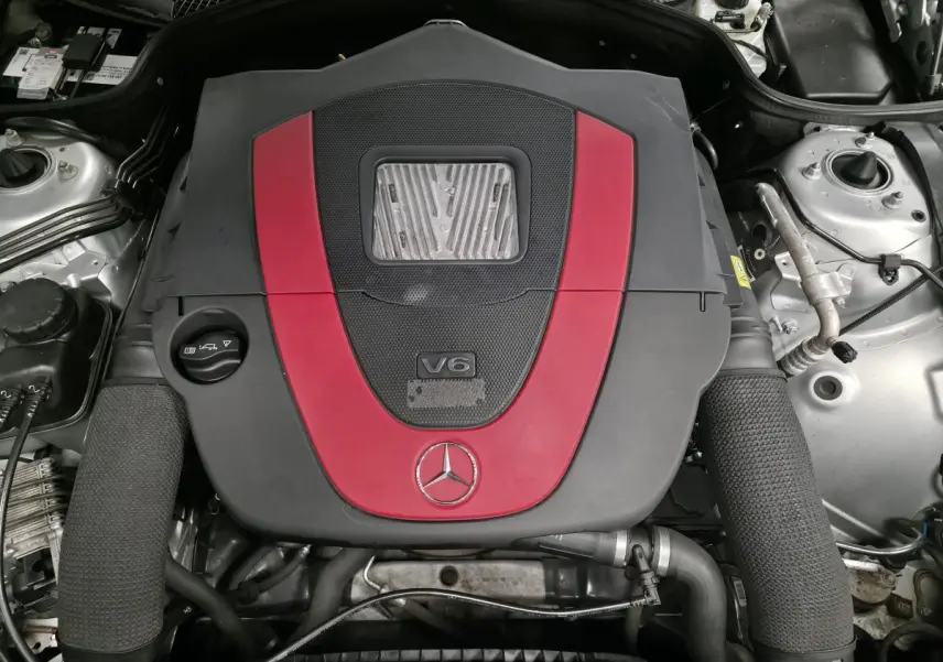 Vue plongeante sur le moteur V6 Mercedes SL 350 avec cache moteur gris et rouge, détail du compartiment moteur.