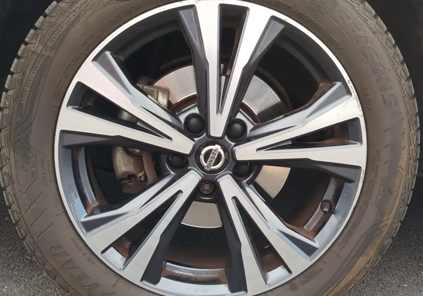 Gros plan sur la jante alliage bicolore du Nissan Qashqai Gris Squale, mettant en valeur le logo central et le disque de frein.