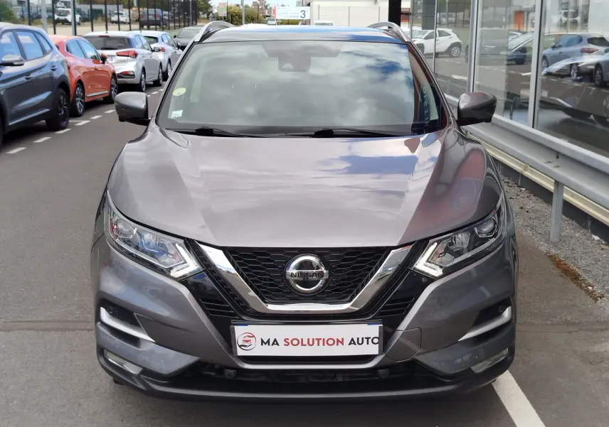Vue frontale d'un Nissan Qashqai gris Squale 2021 avec calandre chromée et phares LED allumés.