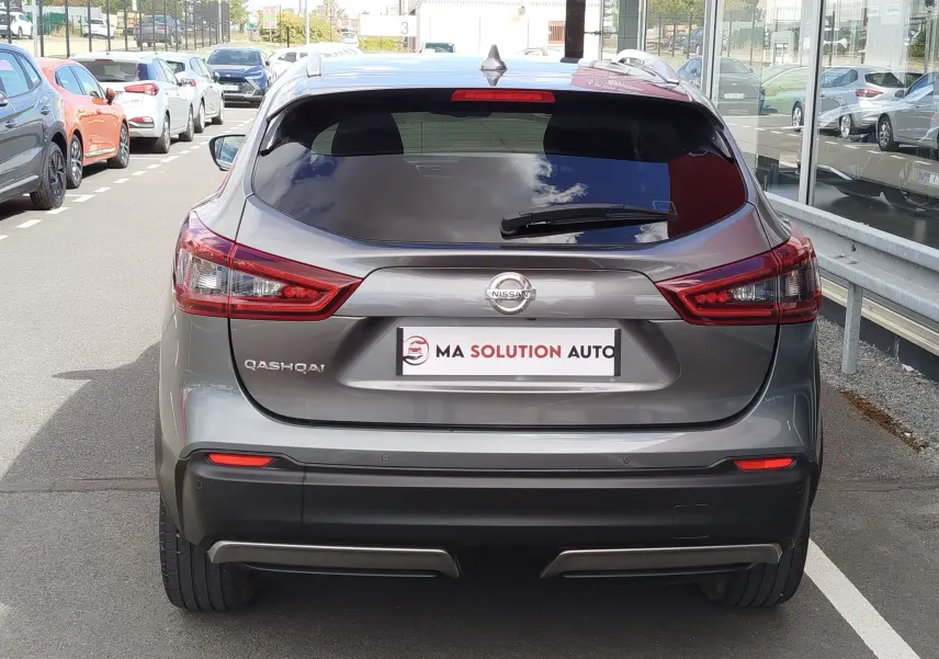 Vue arrière d'un Nissan Qashqai gris Squale 2021 avec feux arrière allongés et logo Nissan bien visible.