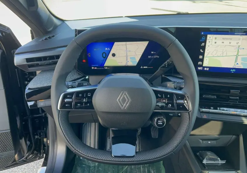 Vue intérieure centrée sur le volant multifonctions de la Renault Clio noir étoilé avec tableau de bord digital et écran tactile.