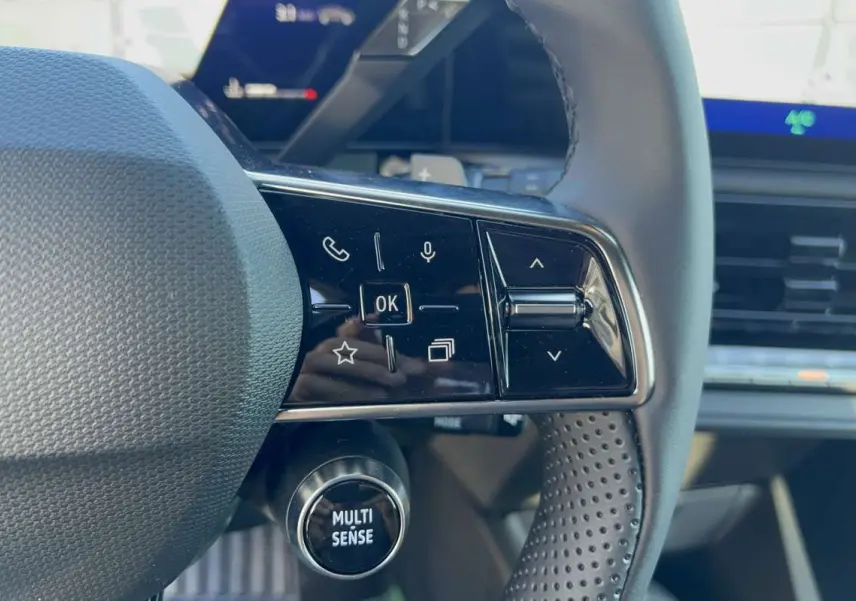 Gros plan sur le volant textile grainé de la Renault Clio noir étoilé, avec commandes multifonctions et bouton Multi Sense.