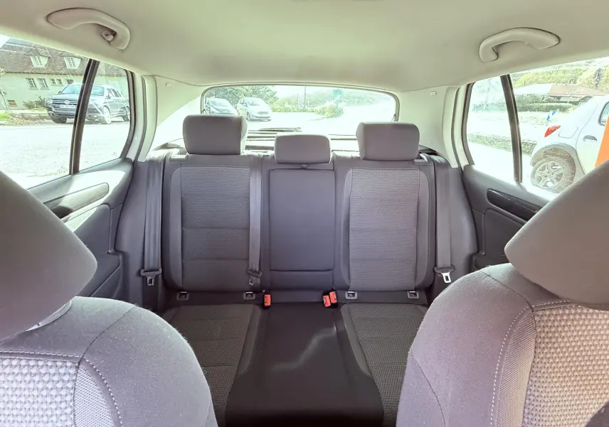 Vue intérieure arrière des sièges arrière en tissu gris noir d'une Volkswagen Golf blanche de 2012, avec appuie-têtes et ceintures visibles.