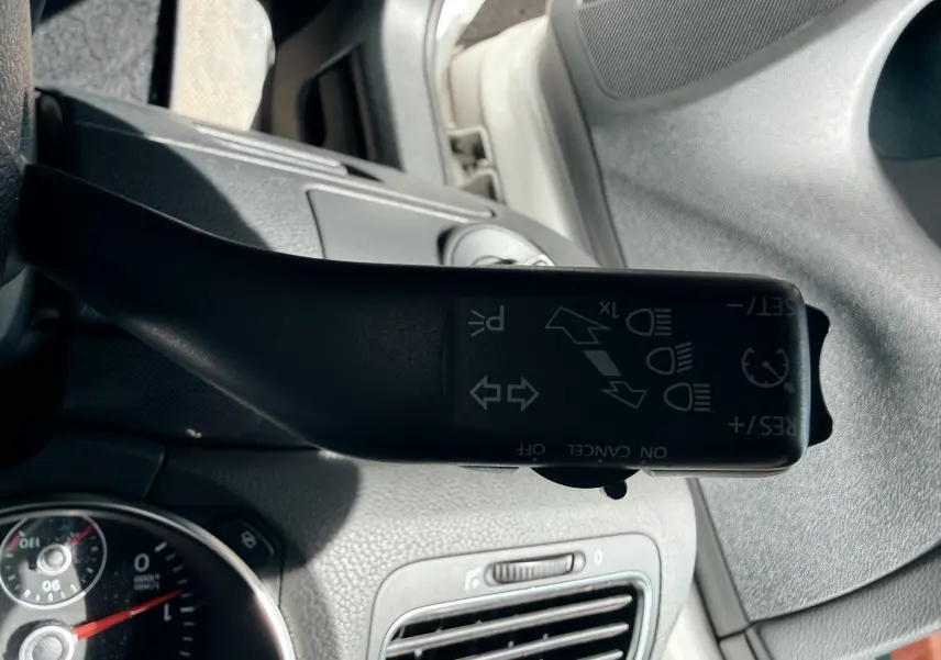 Le levier de clignotant noir de la Volkswagen Golf blanche de 2012, vu de près côté gauche du volant.