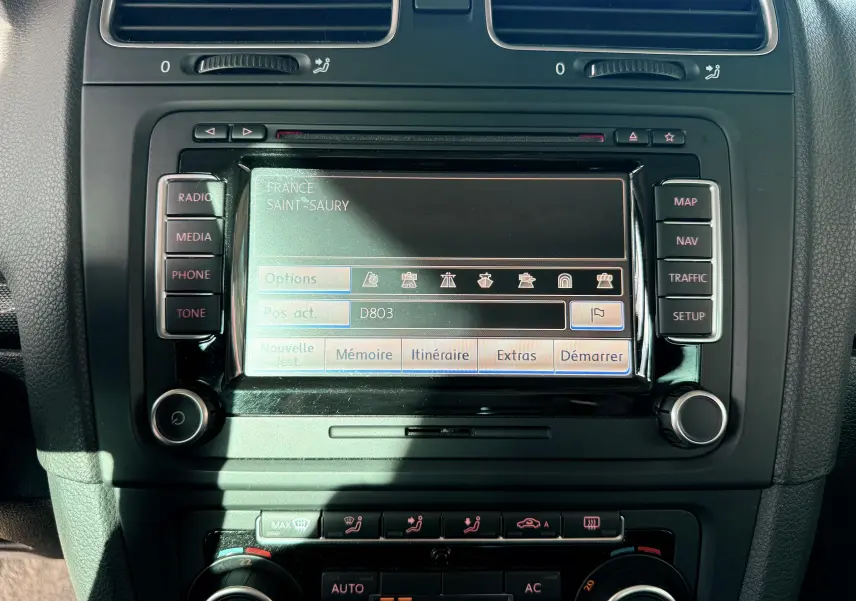 Écran de navigation central avec commandes radio et climatisation dans une Volkswagen Golf blanche de 2012