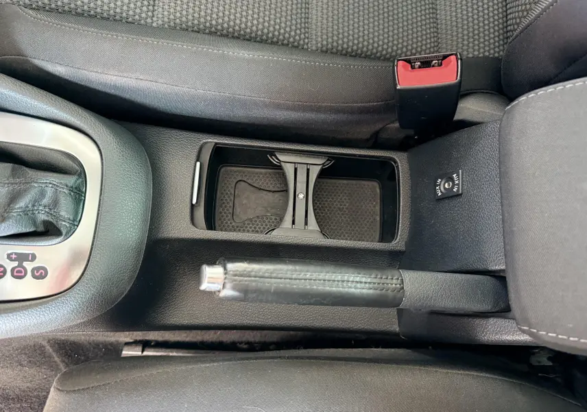 Vue rapprochée de la console centrale d'une Volkswagen Golf blanche de 2012, avec frein à main et prise AUX visible.