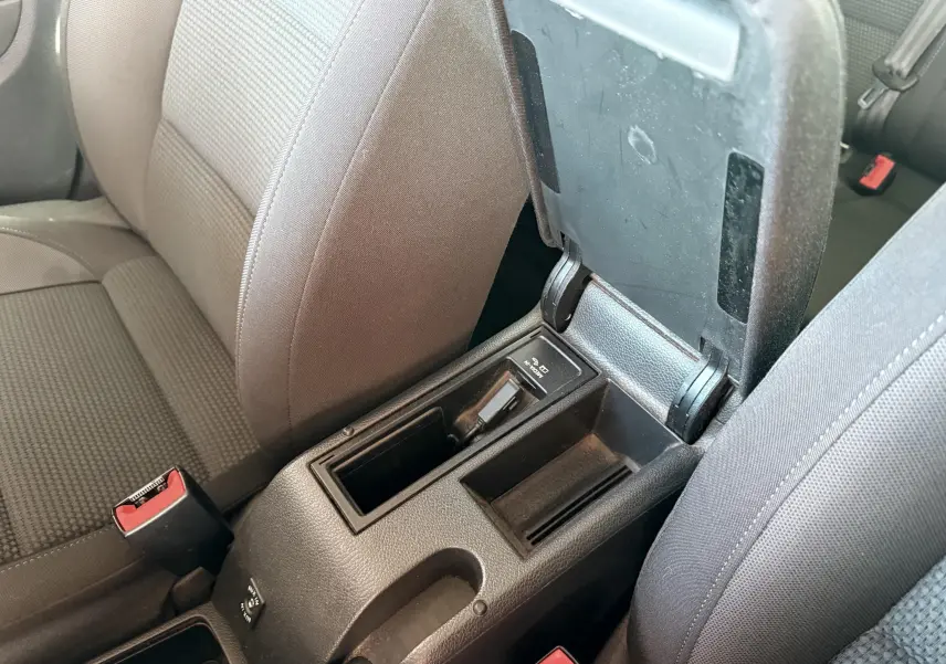 Vue rapprochée de la console centrale ouverte entre les sièges avant gris foncé d'une Volkswagen Golf blanche de 2012.